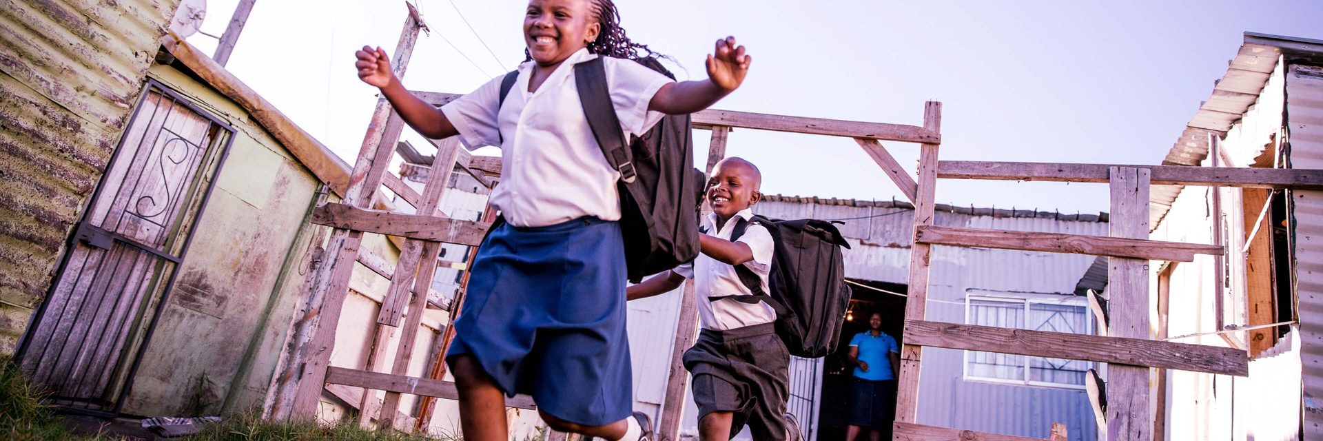 Three children skipping out of school at the end of the day.