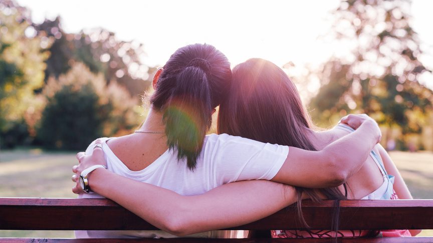 Two people embraced on a park bench.