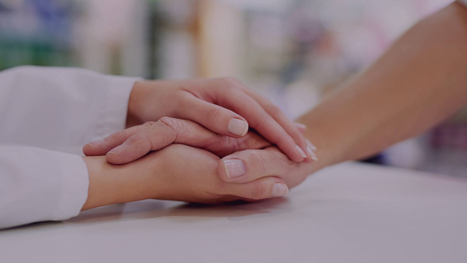 Two hands embracing across a desk